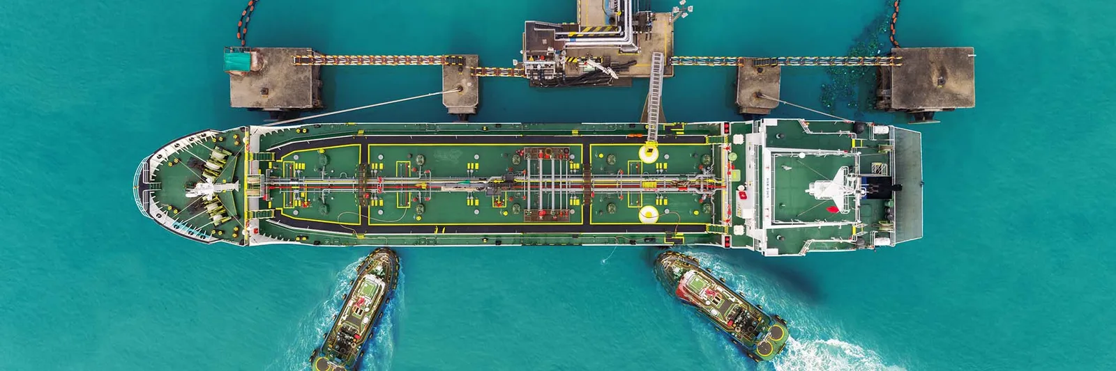 Large tanker vessel being guided to a jetty by tugboats, illustrating marine technical survey context